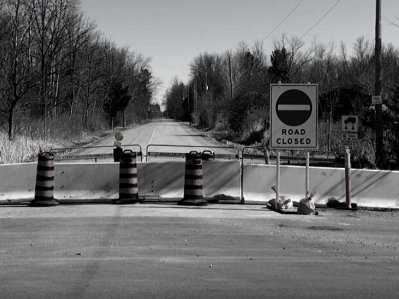 A closed off road with stop signs in front of a concrete barrier