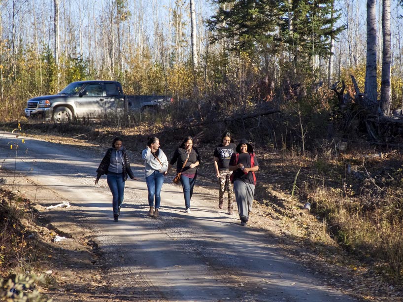 Five women walk down a gravel road