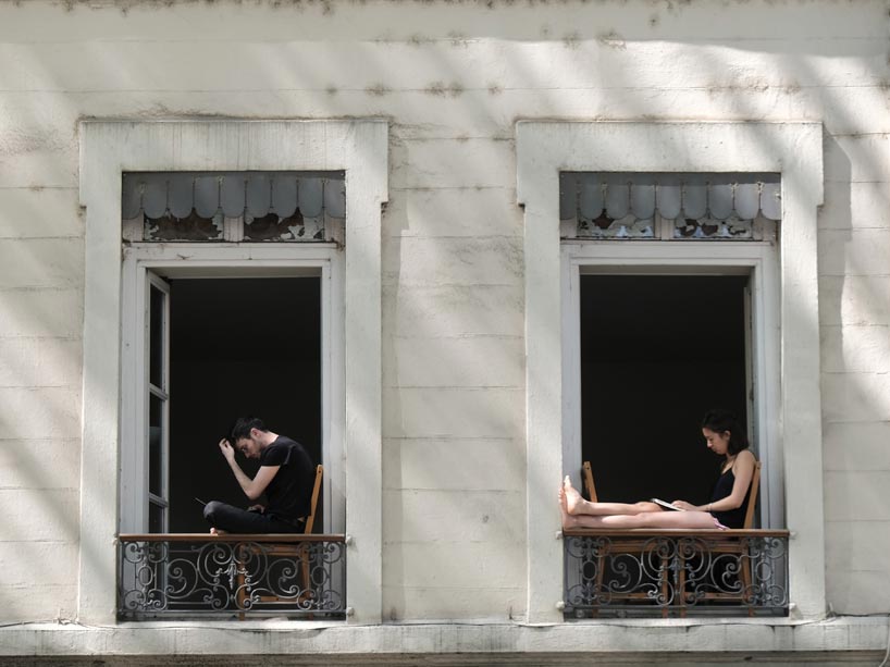 Two people sitting on their window sills in a building