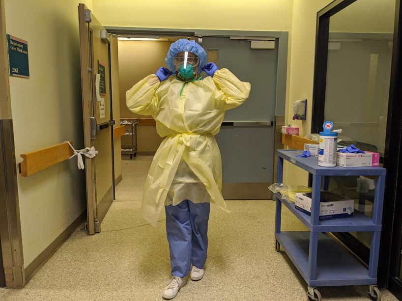 A health care worker in personal protective equipment walking within a hospital