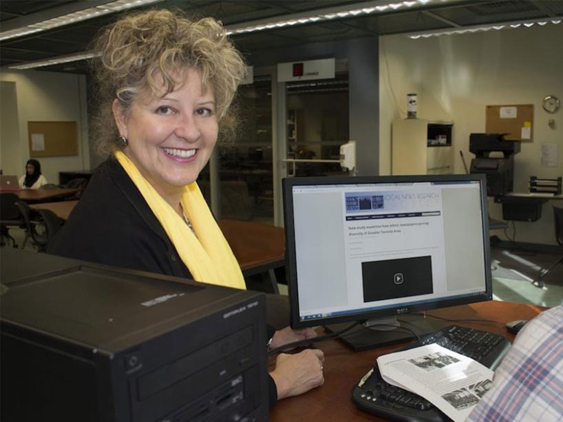April Lindgren stands in front of a computer displaying the Local News website