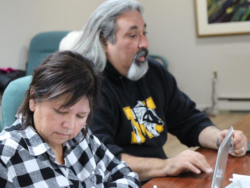 Man and woman sit at a desk in a classroom setting.