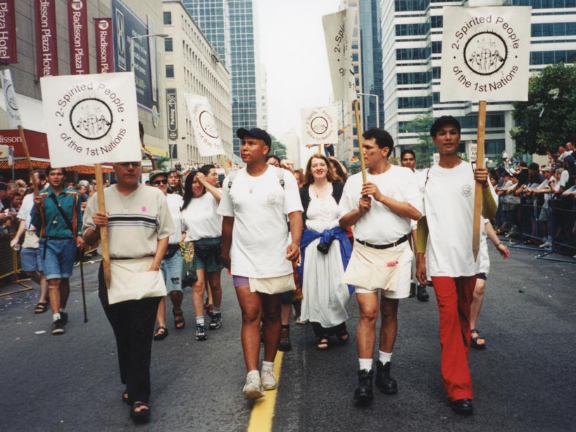A group of people march in Toronto Pride in the 2000s with signs.