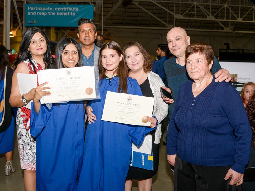 Family members gathered around two graduates dressed in their blue robes