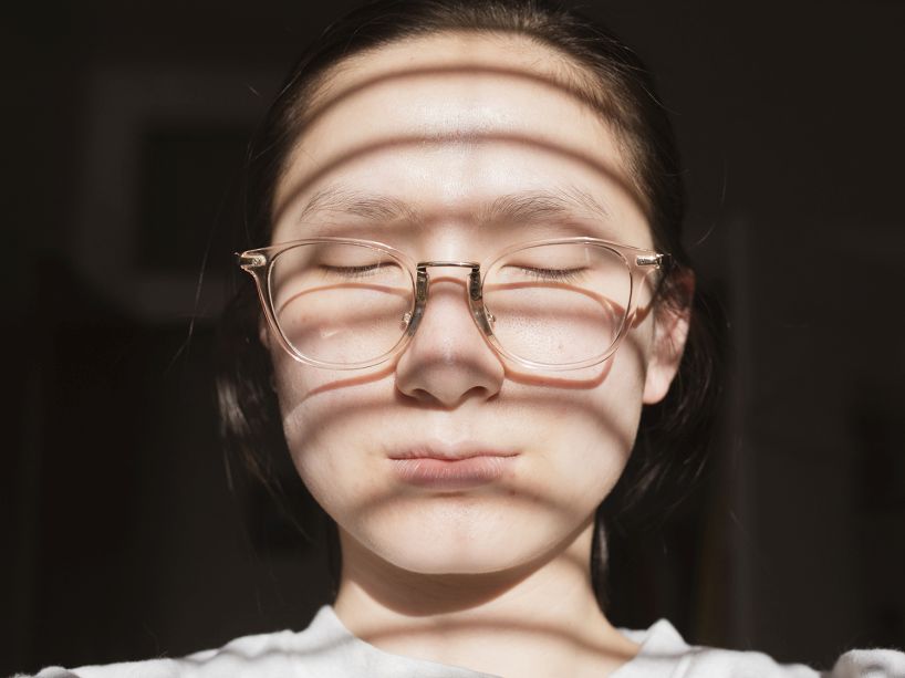 A woman with the reflection of window blinds on her face