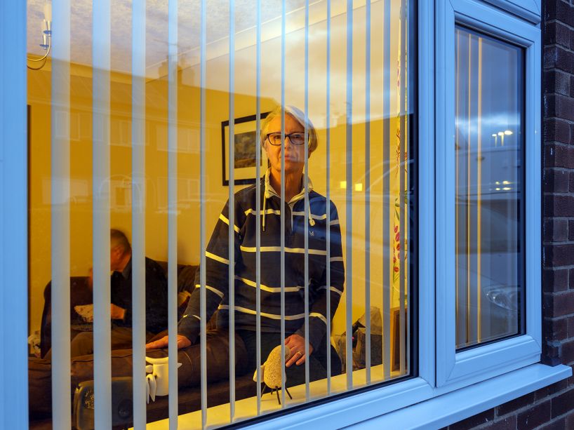 A person through an apartment window, seen between window blinds