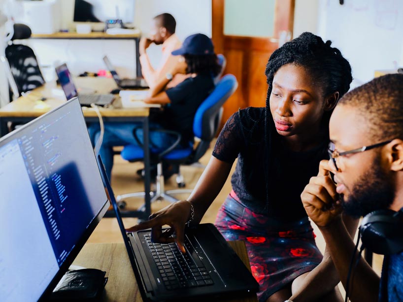 Two people discussing information on a computer screen