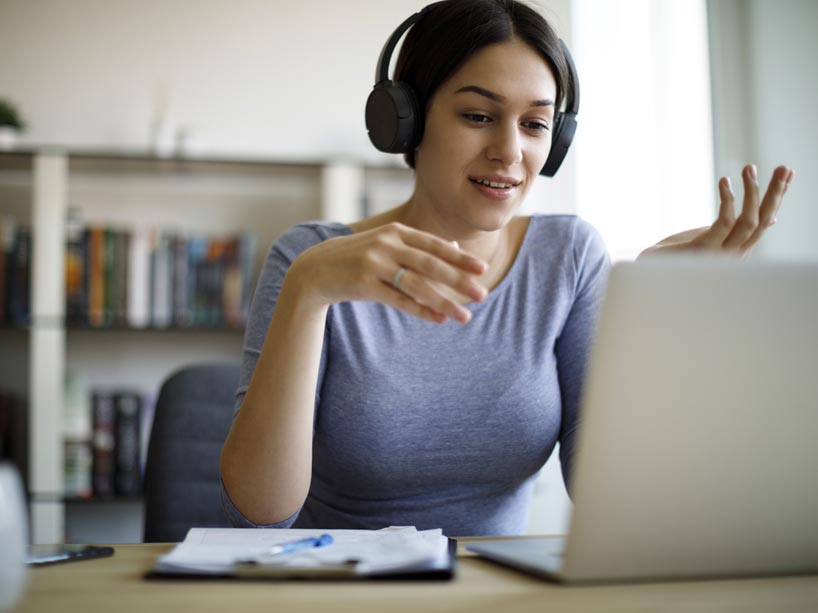 A young woman takes a video call on her computer from home