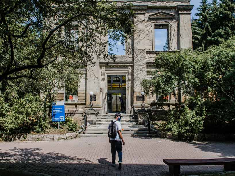 A student wearing a mask walking up steps into the Ryerson Athletic Centre