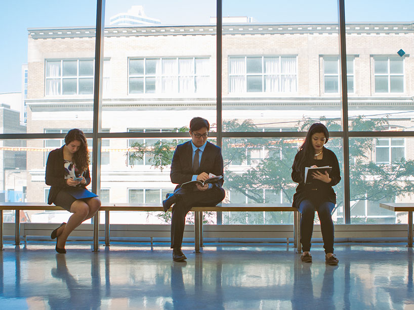 3 students sit in chairs waiting for job interviews