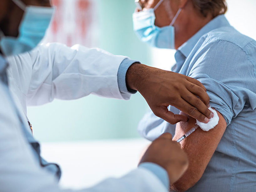 Man wearing a face mask receiving flu shot from doctor