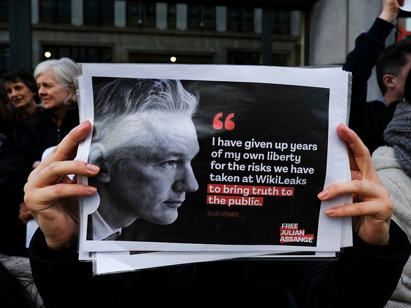 A protestor holds a sign with a photo of Assange that says I have given up years of my own liberty for the risks we have taken at WikiLeaks to bring truth to the public.
