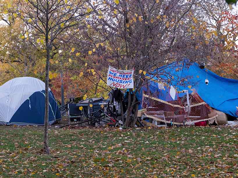 Encampment in Toronto with sign Winter is coming. We need permanent housing now