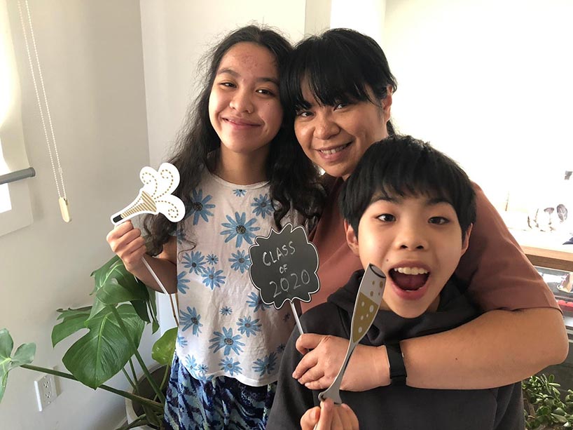 Sze Wan (Kittie) Pang smiles with her arms around her children, who are holding celebration signs