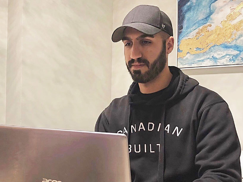 A man sits at a table typing on his computer