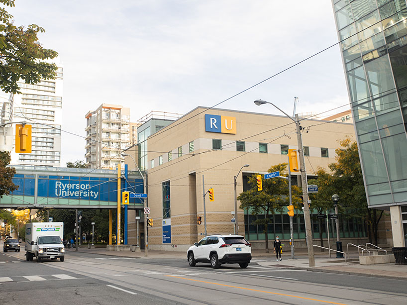 Two cars driving on Church Street in front of Ryerson University buildings