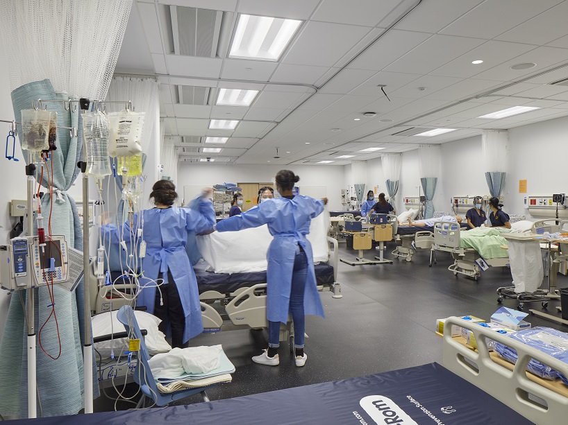 Nursing students attend to a simulation patient in a hospital ward.