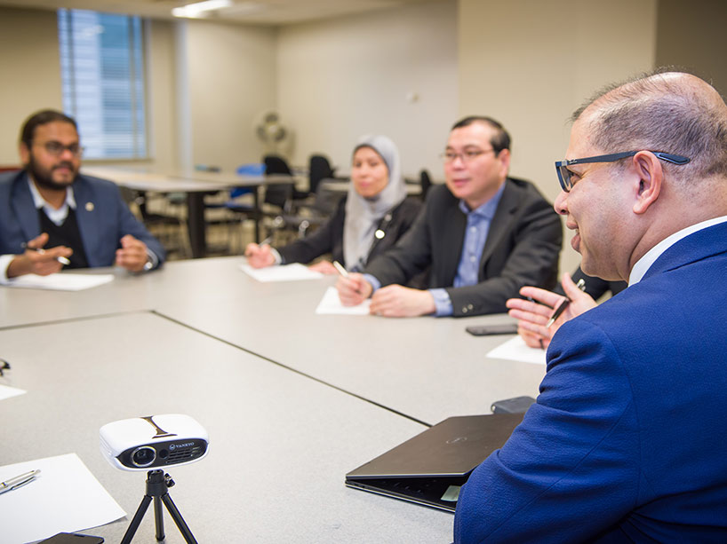 Dr. Shafi Bhuiyan teaches a group of internationally trained doctors around a table.