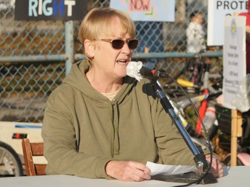 Cathy Crowe speaking at a microphone at a demonstration.