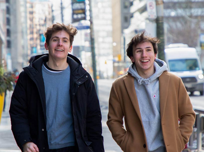 Ryerson film students Charlie Hill, left and Max Mezo, right, are seen smiling and walking down a Toronto street.