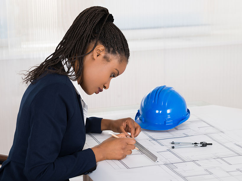 A female engineer draws on blueprint