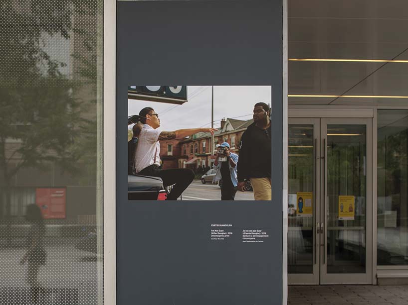 Randolph’s photo of a man in a white shirt pointing at another man in a black sweater as displayed on campus.