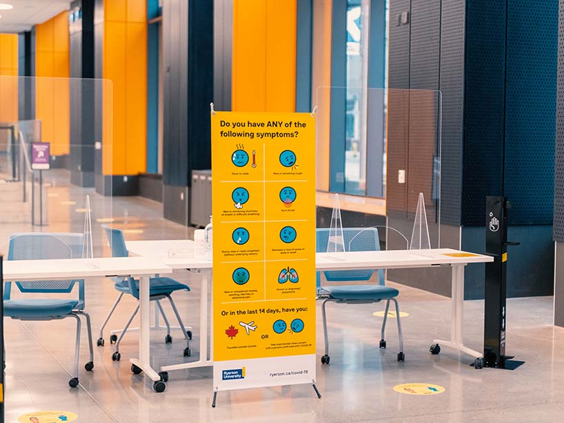 Check-in desk at the vaccine clinic with a sign asking visitors to check for COVID-19 symptoms