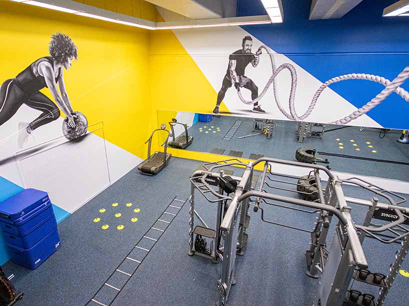 A corner shot of Ryerson’s Recreation and Athletics Centre showing workout equipment and illustrations on the wall
