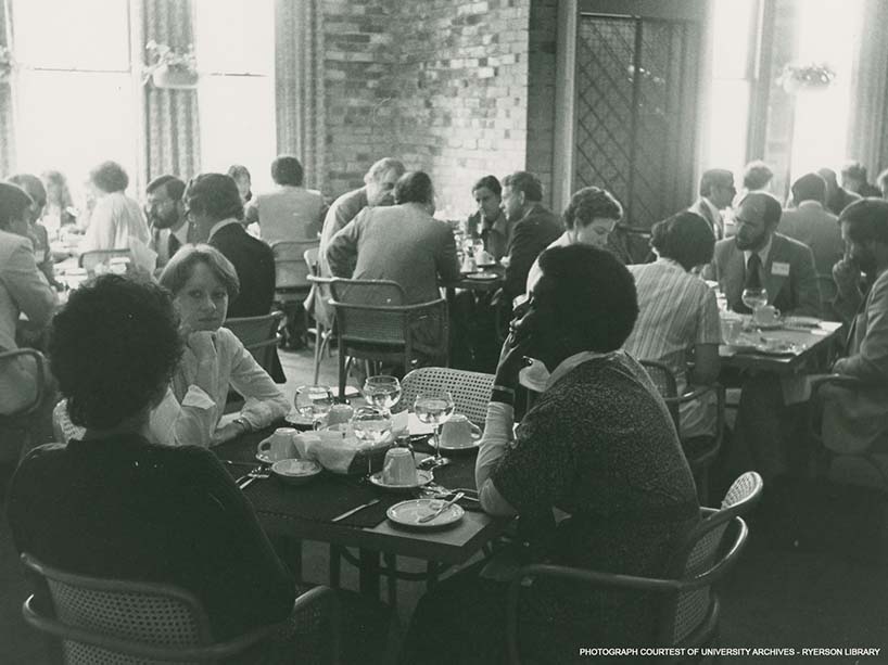 A dining room with groups of people sitting around tables with chairs.