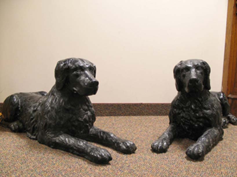 Cast iron sculptures of two dogs sitting.