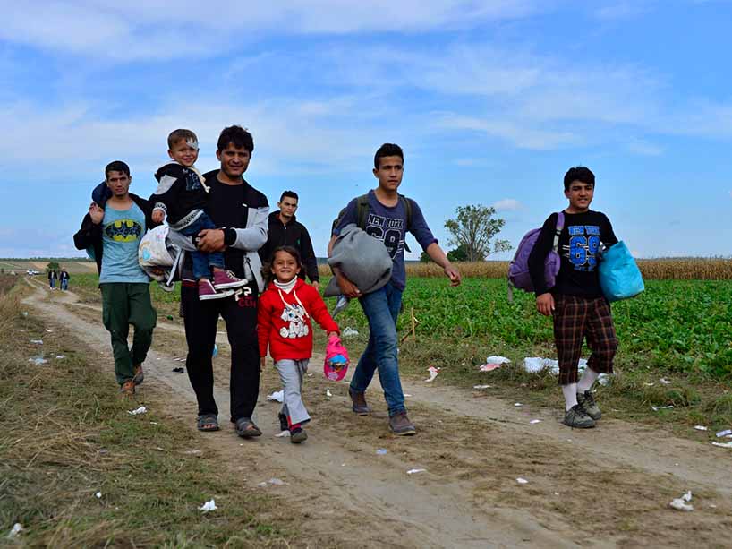 A group of children and adults from Afghanistan walk through a field in Serbia in 2015.
