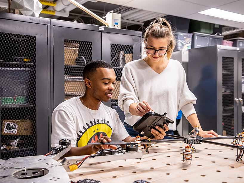  A Black male and white female student from the Design Fabrication Zone shown working together on a project 