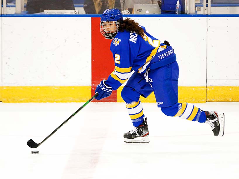 A member of the Rams women’s hockey team skates with the puck