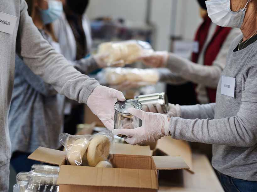 An assembly line of volunteers packing food boxes.