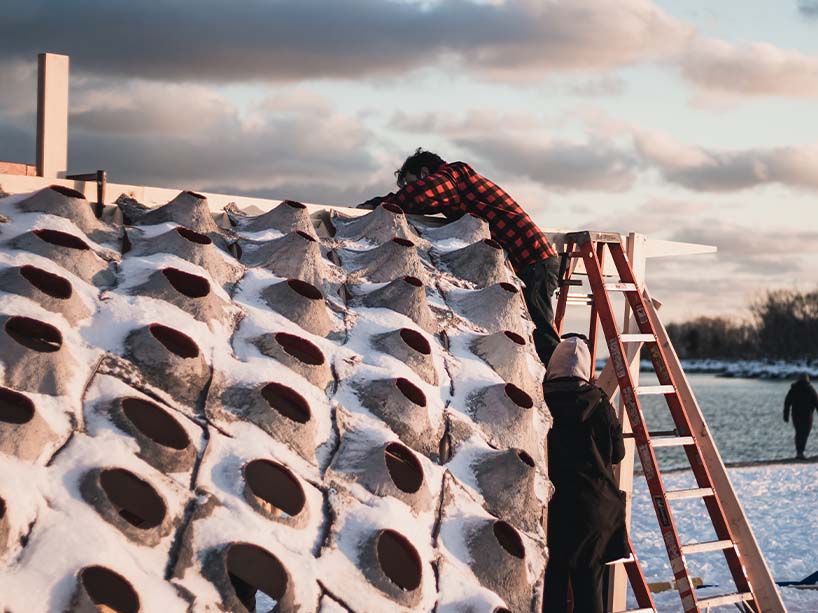 Two people build a structure on a beach