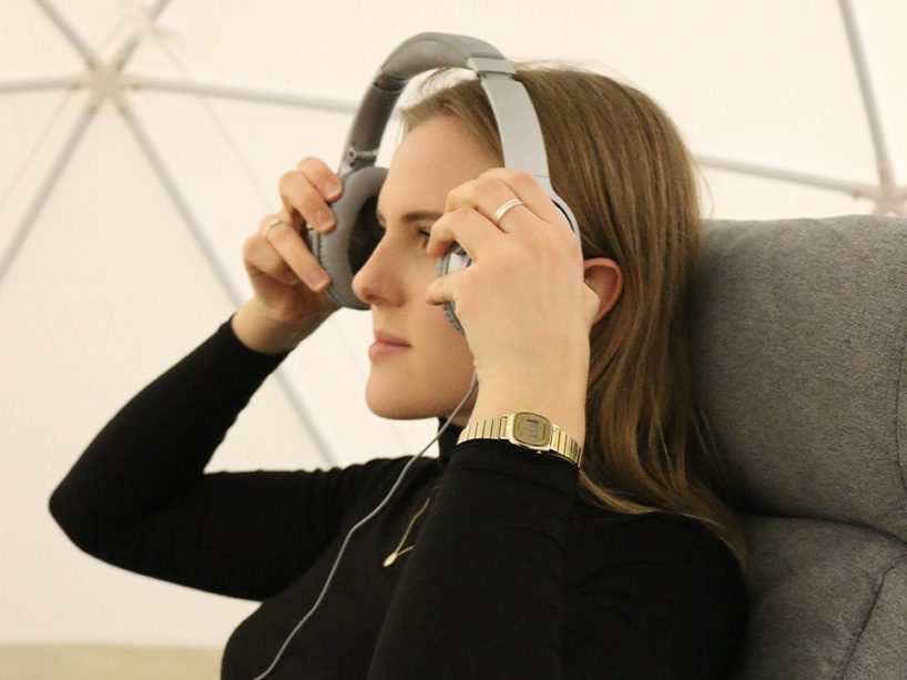 A woman sitting on a chair putting headphones on.