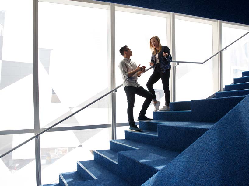 Two individuals engaged in conversation on a blue staircase.
