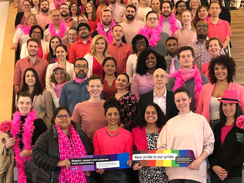 The university community posing for a photo with pink garments and accessories on.