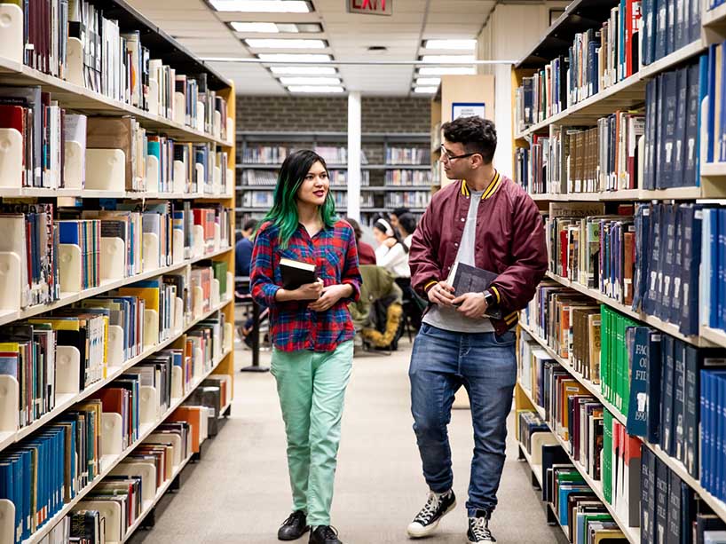 Two people walking in the library.