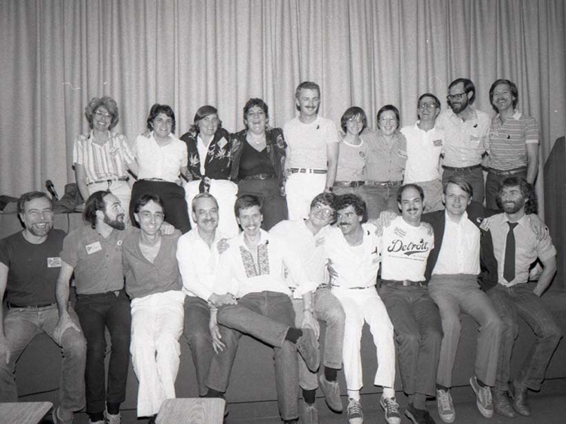 A Black and white photo of two rows of men and women side by side with arms around each others shoulders in a show of solidarity at the conference