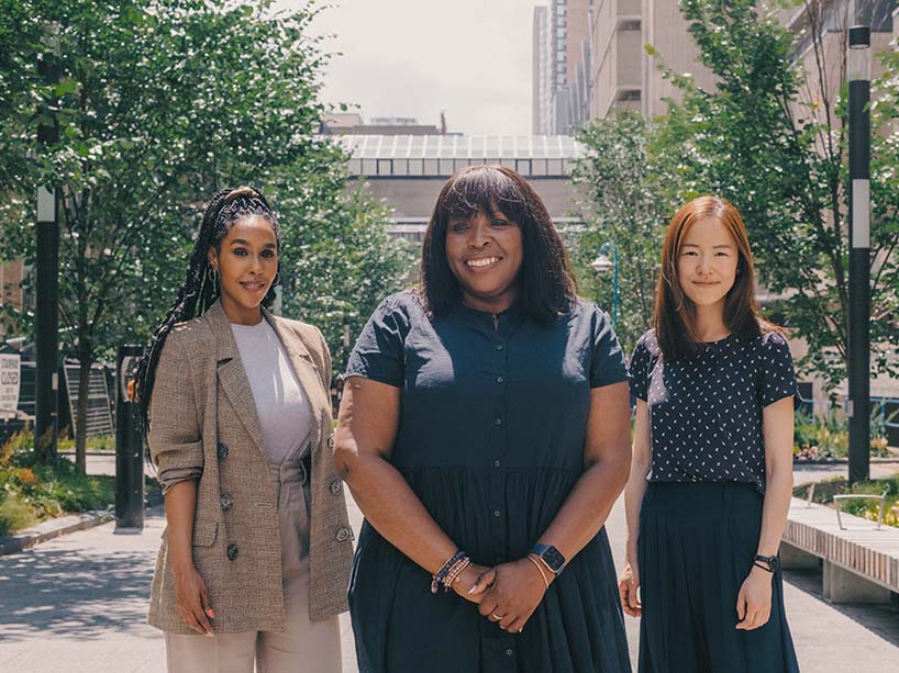 Three women standing outside together on a sunny day.