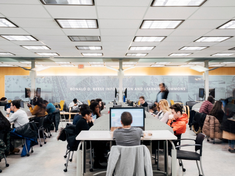 Students sit around tables in the Library and study.