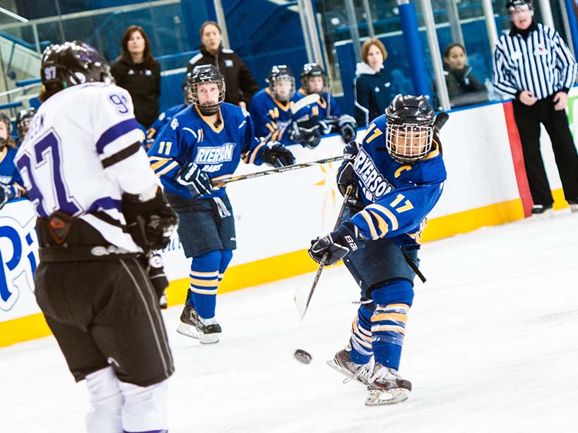 Nella Brodett shoots a puck while playing hockey for TMU