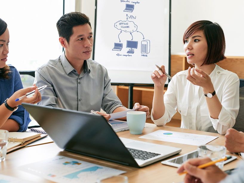 A group of people working around a table together.
