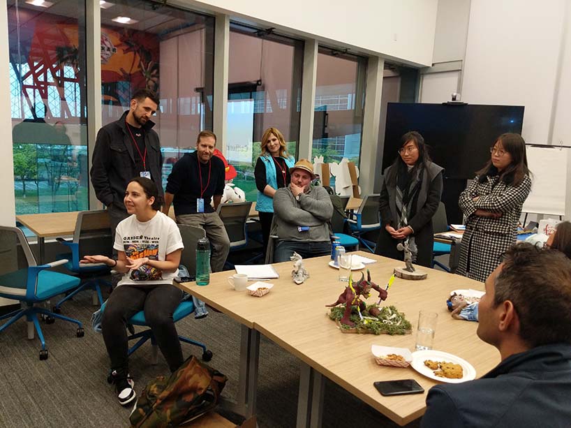 Students in a classroom discuss a toy prototype that sits on a table