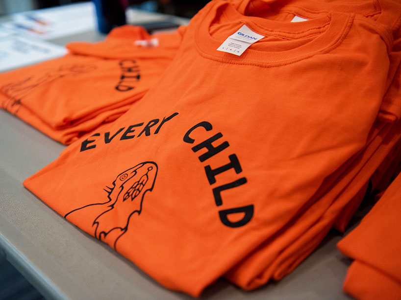 Close-up of an orange t-shirt that says Every Child