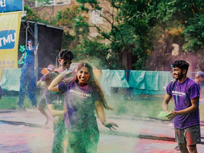 Students in the midst of throwing brightly coloured powder on eachother.