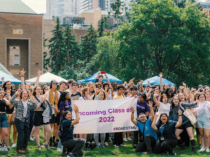 Numerous students pose for a group photo with a large sign reading ‘Incoming Class of 2022’