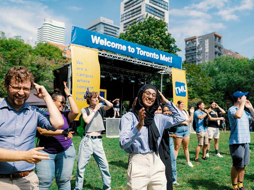 Community members outside dancing in front of a stage with a sign that says “Welcome to Toronto Met!”