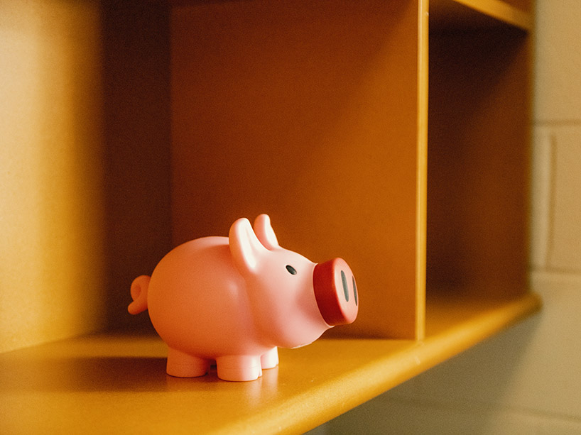 Pink piggy bank sits on a wooden shelf